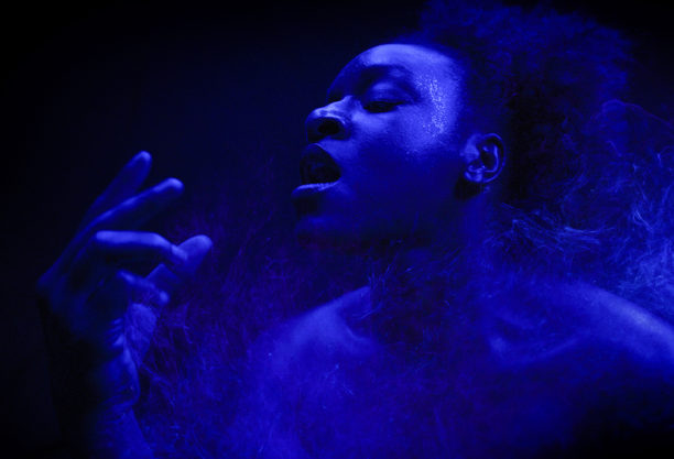 A still of a figure surrounded by smoke under blue lighting.