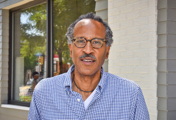 headshot of fellow louis massiah standing outside in a blue checked shirt.